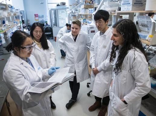 students gather in lab around student with notes