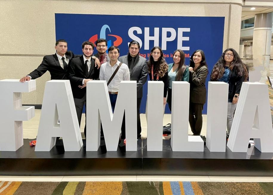 SHPE students in front of large white letters spelling "FAMILIA"
