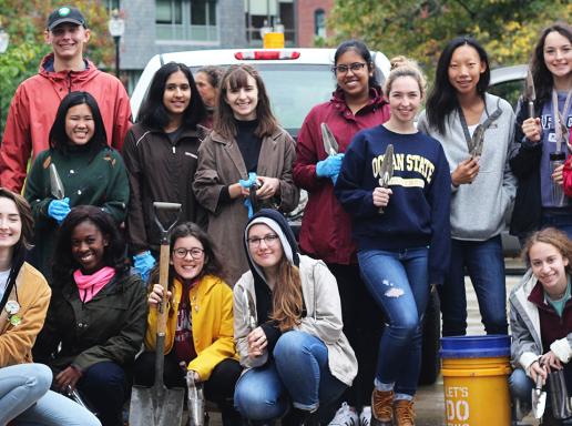 Honors College students posing outdoors with gardening tools