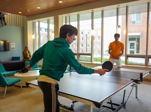 Two students play ping pong in a residence hall at the University of Massachusetts