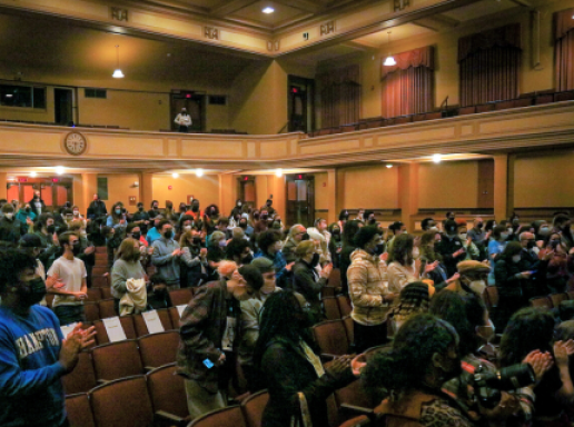Audience members stand and applaud at an event at the University of Massachusetts