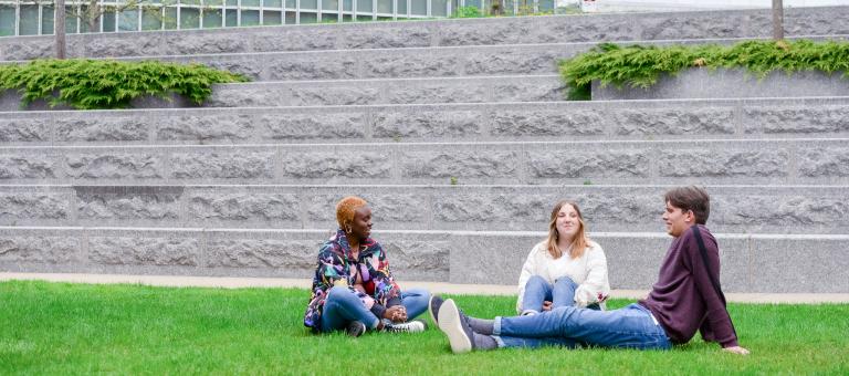 Three students sit outdoors at Commonwealth Honors College at the University of Massachusetts
