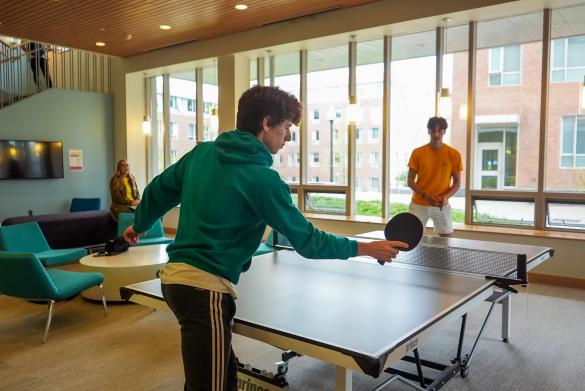Two students play ping pong in a residence hall at the University of Massachusetts