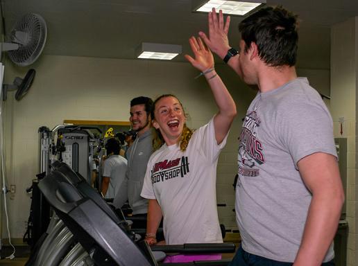 Kinesiology students walking on treadmills give each other a high five