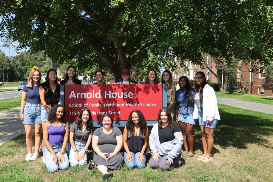 Students sitting and standing around the Arnold House sign.