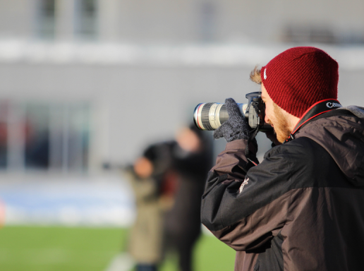 Student on a sports field, taking pictures of the action.