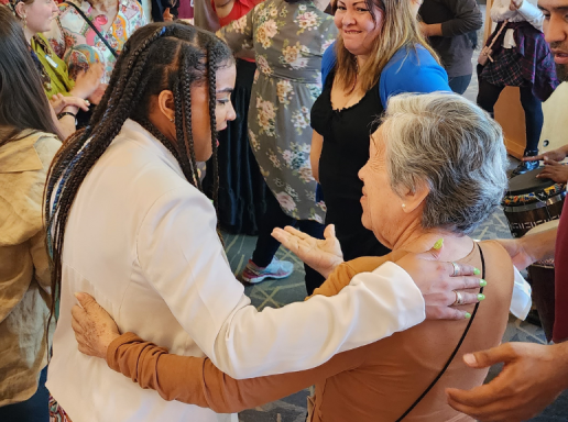 CLACLS student embracing an elderly woman at a crowded event. 